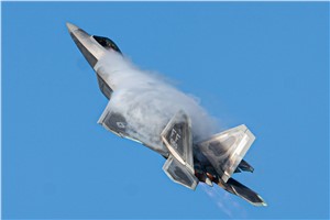 An F-22 flies across a blue sky